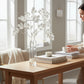 Mellow Monkey 36-inch white leaf spray in a glass vase on a wooden table, adding winter elegance to home decor.