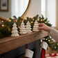 Mellow Monkey set of six white stoneware Christmas tree figurines displayed on a wooden mantel with holiday decor.