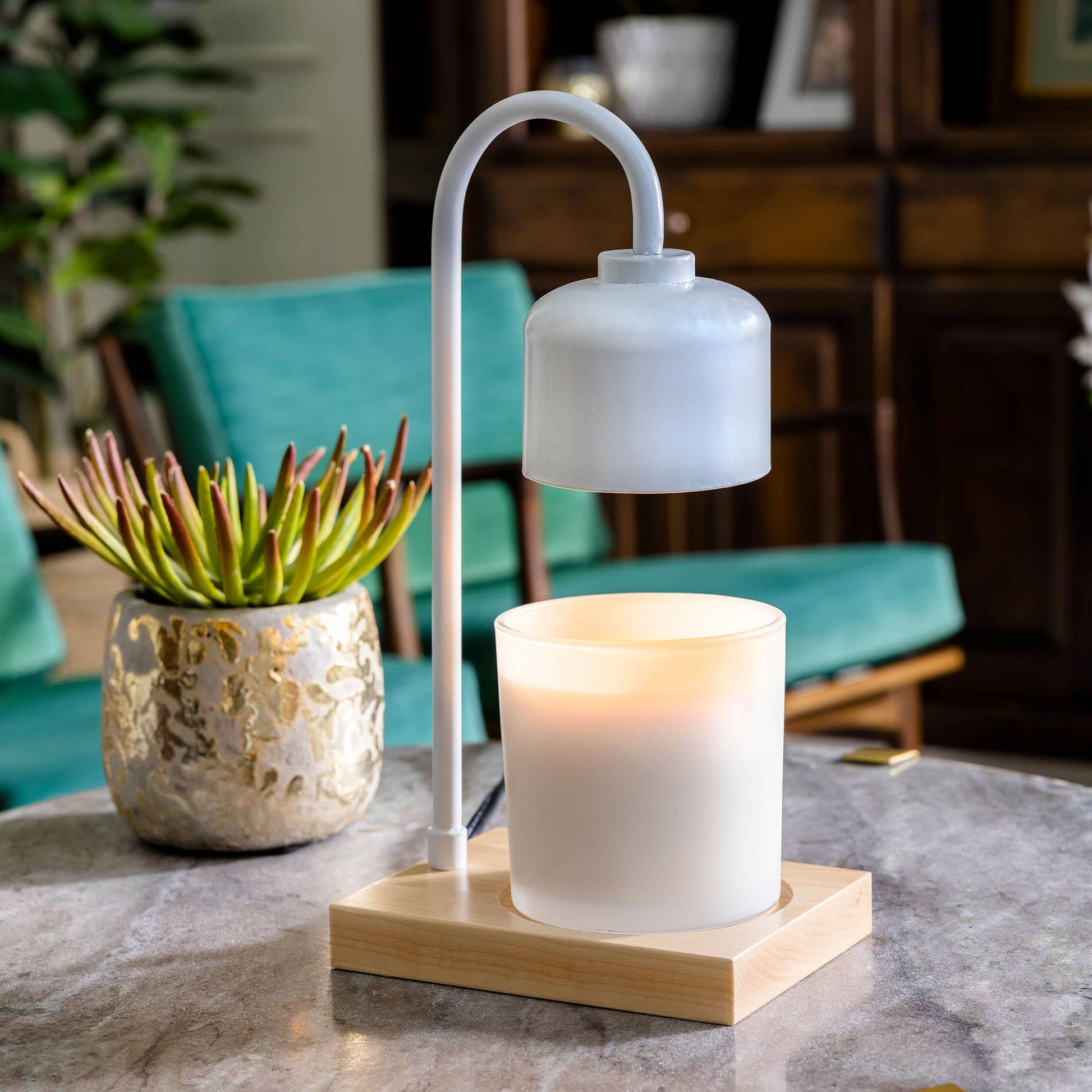 Mellow Monkey white arched candle warmer lamp with a natural wood base and glowing jar candle on a marble table