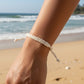Mellow Monkey white woven cotton nautical bracelet on a wrist with a beach background