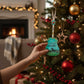 Mellow Monkey hand-painted Wild Horses guitar ornament hanging on a Christmas tree with a cozy fireplace background.