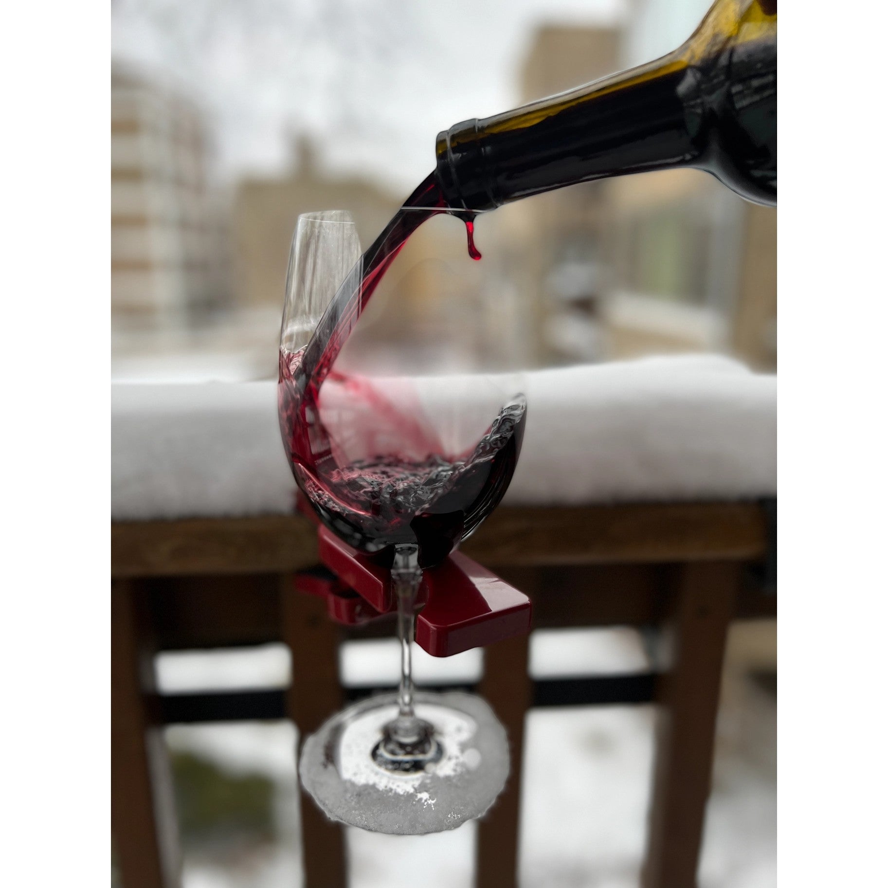 Mellow Monkey red wineGrasp wine glass holder clipped to a wooden railing with red wine being poured into a glass