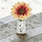 Mellow Monkey white stoneware vase with Winnie the Pooh illustration and a heart, holding a yellow and red dahlia.