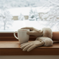 Mellow Monkey winter white microsuede gloves with faux fur cuffs and rhinestone bit detail held near a snowy window