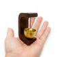Mellow Monkey 3-inch door chime with a dark wood frame and a gold metal bowl held in a person's palm.