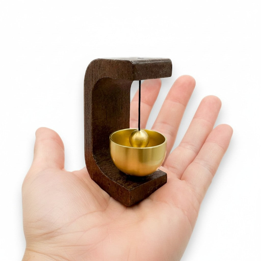 Mellow Monkey 3-inch door chime with a dark wood frame and a gold metal bowl held in a person's palm.