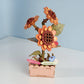 Mellow Monkey DIY wooden sunflower puzzle kit with orange and brown petals, green leaves, and a pink planter. Features "Happy Birthday" and "Congratulations" signs.
