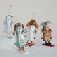 Mellow Monkey handcrafted wool felt dog ornaments wearing quilted coats and holding skis on a snowy surface