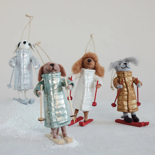 Mellow Monkey handcrafted wool felt dog ornaments wearing quilted coats and holding skis on a snowy surface