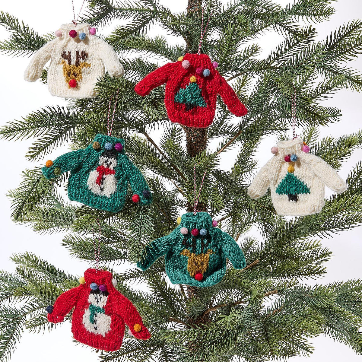 Mellow Monkey hand-crafted wool sweater ornaments with festive holiday designs hanging on a Christmas tree