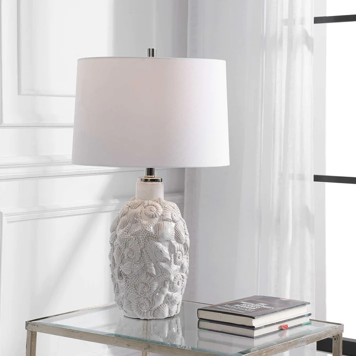white table lamp with seashell relief pattern staged in white living space